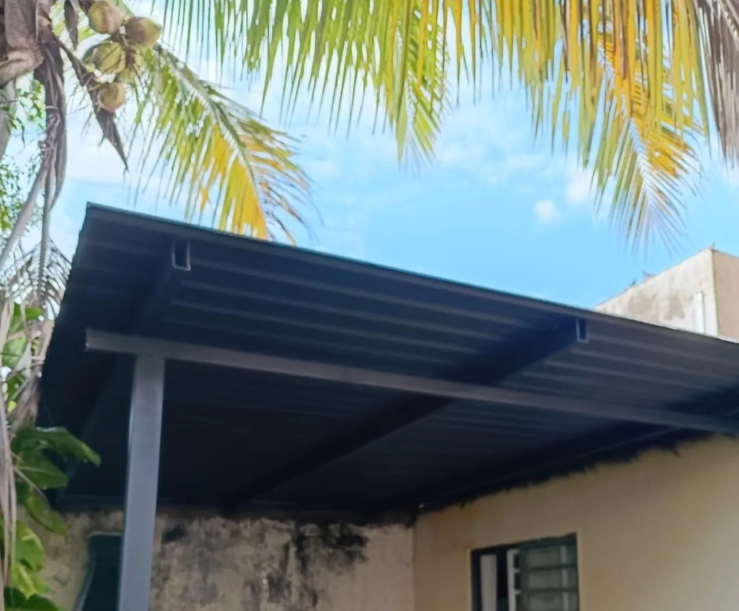 Cobertura de telha metálica escura sobre o quintal de uma casa